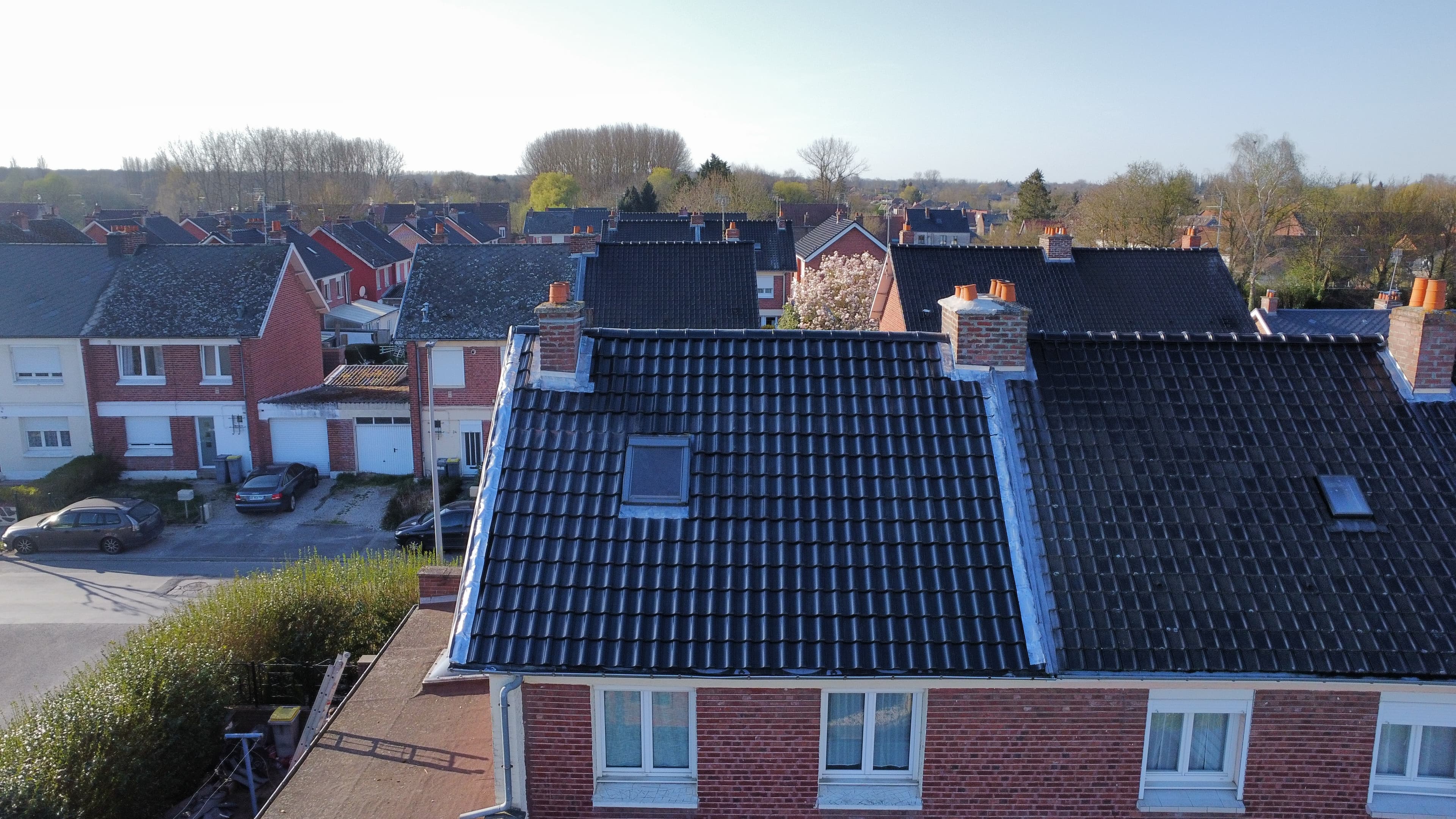 Maisons en briques rouges aux toits sombres dans un quartier résidentiel calme et verdoyant.