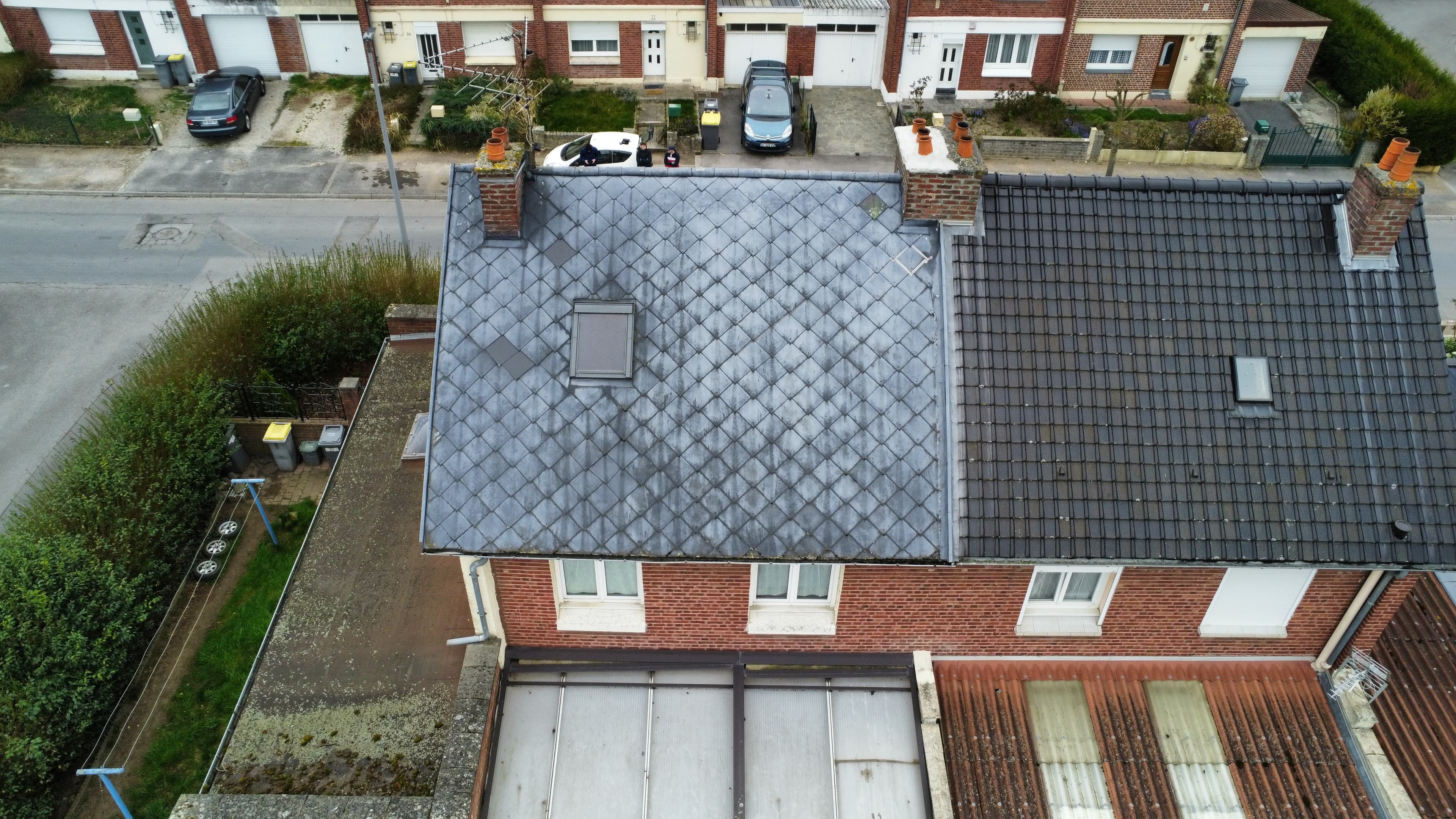 Toiture en ardoises grises et tuiles sombres d'une maison en briques, vue de dessus.